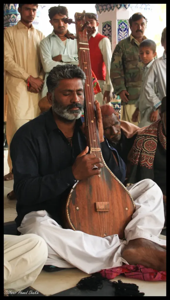 Folk singer playing the tamburo and reciting Shah Abdul Latif verses at Bhit Shah