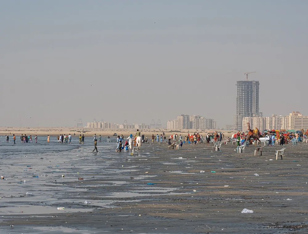 Visitors walking on the sand at Karachi Clifton Beach beside the Arabian Sea