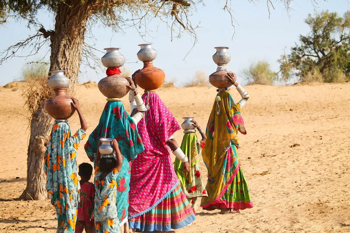 Thari women in colourful dresses carrying water pots home in Tharparkar